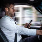 A middle aged caucasian man distracted driving while using a mobile device stops his vehicle suddenly to avoid an accident