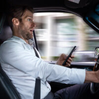 A middle aged caucasian man distracted driving while using a mobile device stops his vehicle suddenly to avoid an accident A middle aged caucasian man distracted driving while using a mobile device stops his vehicle suddenly to avoid an accident